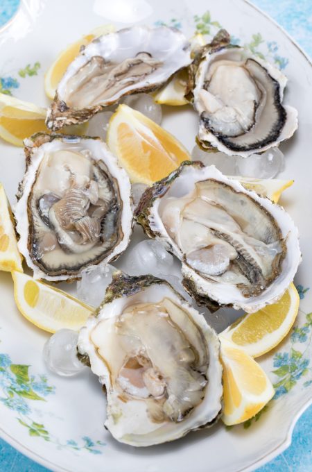 Plate with raw oysters and lemon slices on ice.